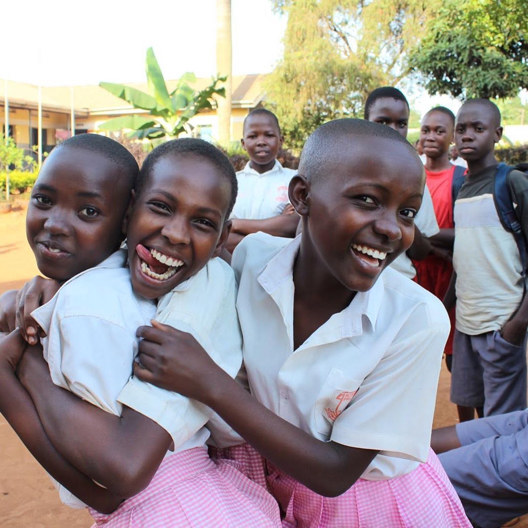 Students in school uniform laughing together outside their classroom
